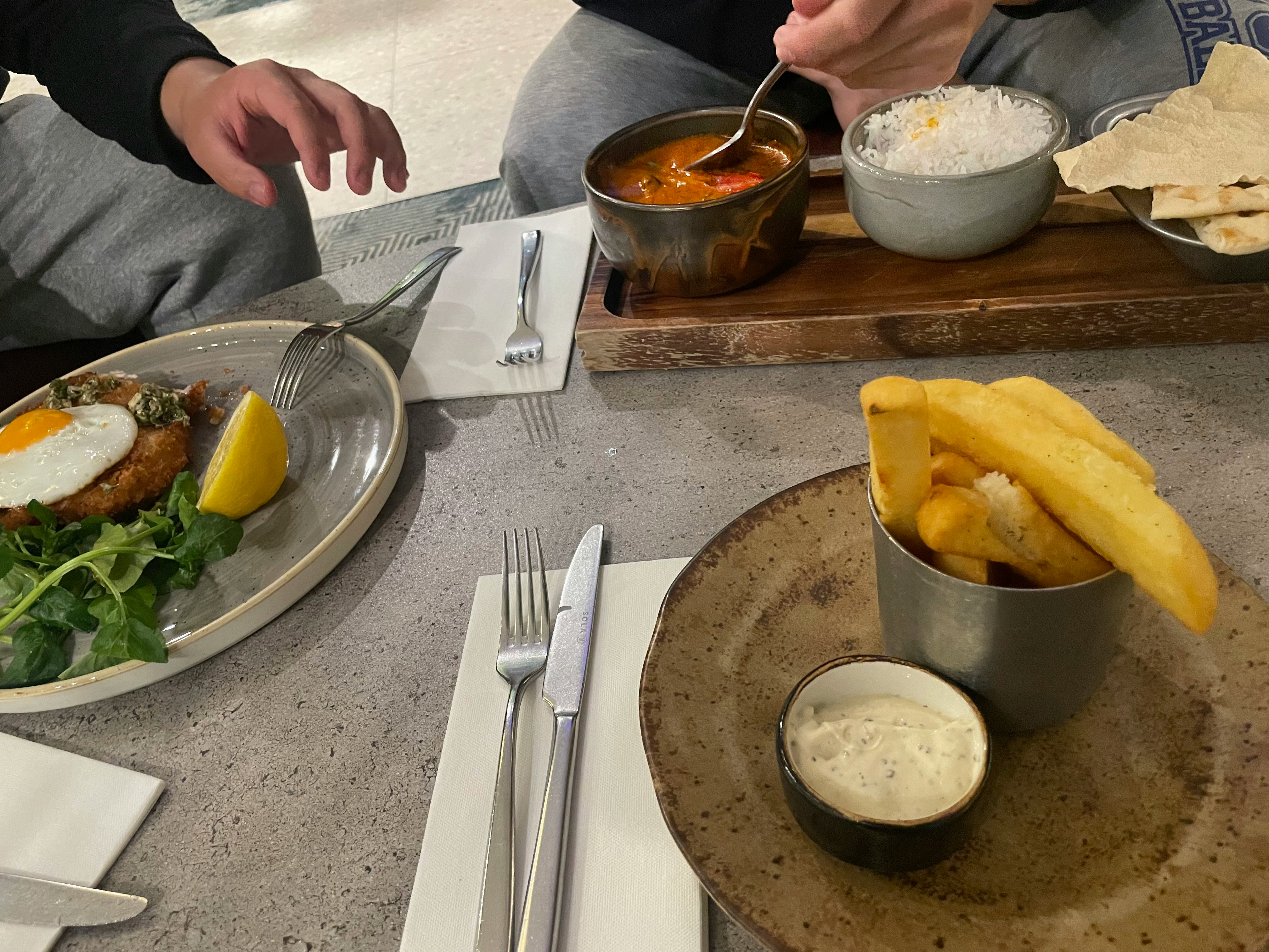 テーブルに並ぶカレーとナン、ポテトチップスの食事