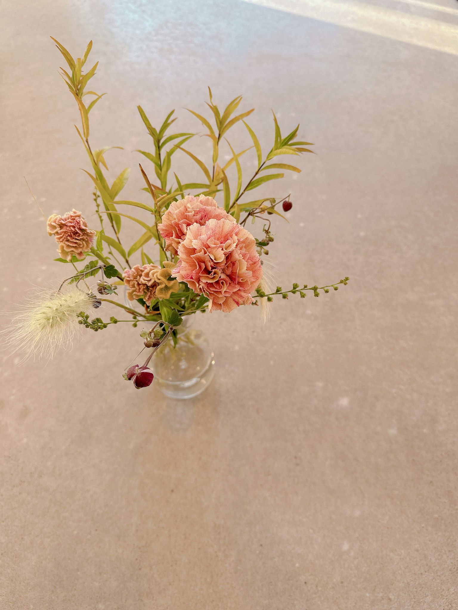 Petit vase avec des fleurs roses et des feuilles vertes