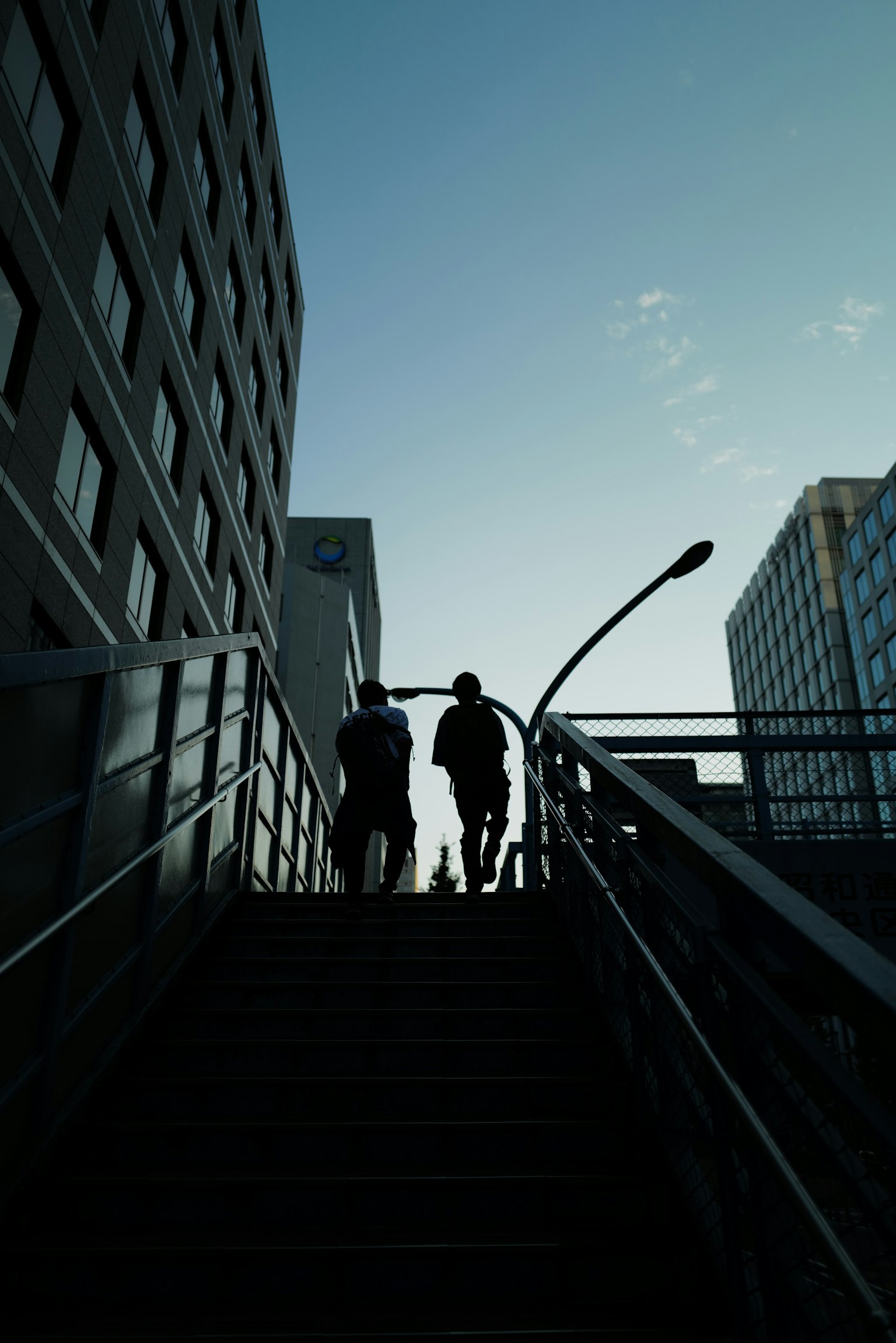 Silhouette de deux personnes montant des escaliers avec des bâtiments en arrière-plan