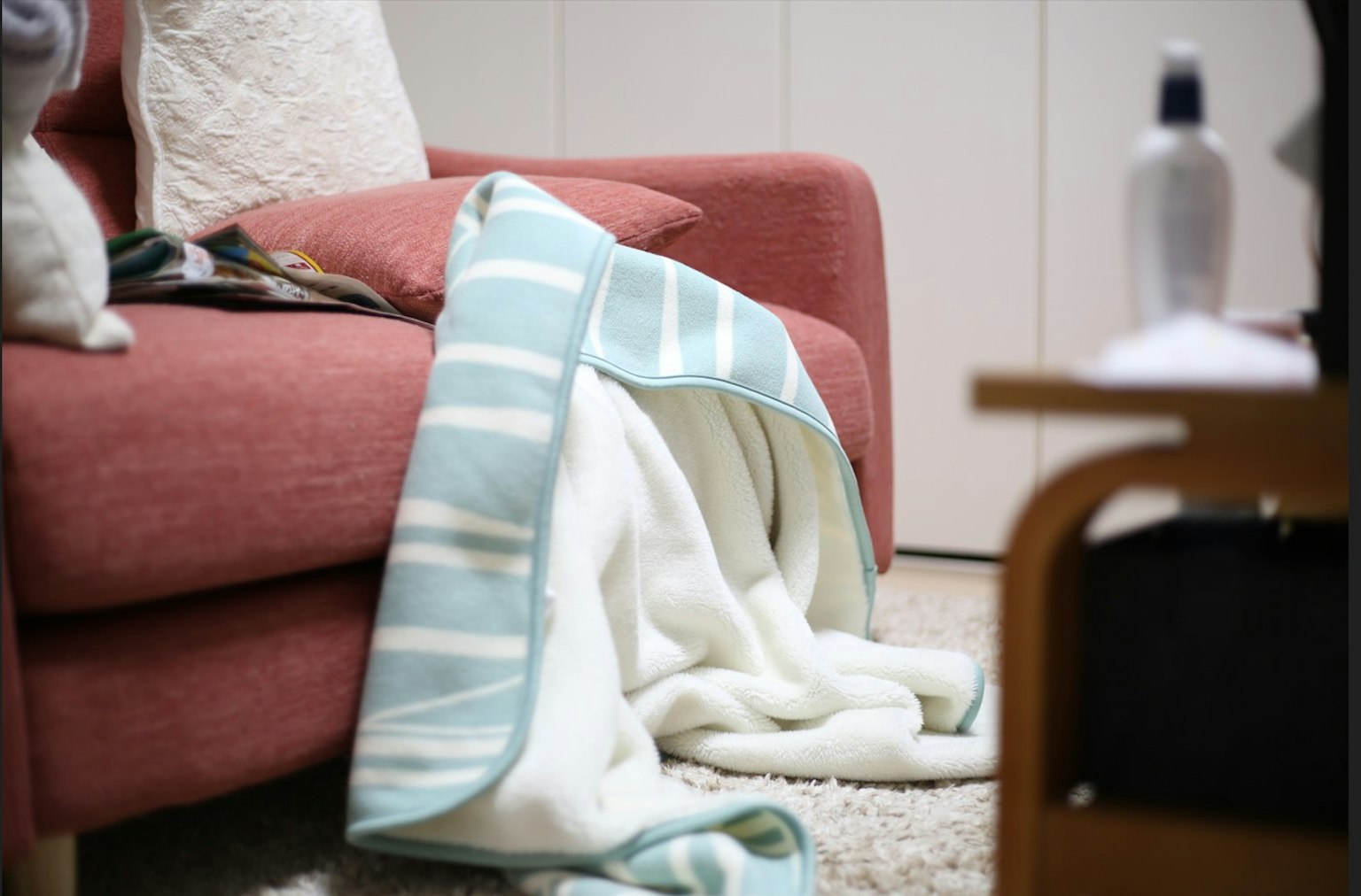 Cozy corner of a living room with a soft blanket draped beside a pink sofa