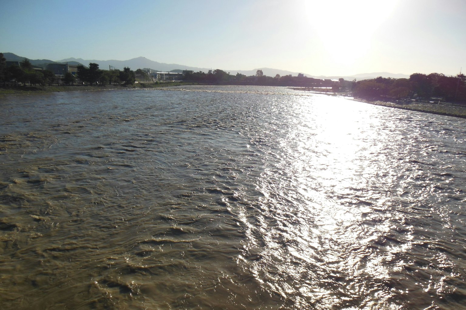 Calm river flowing with sunlight reflections
