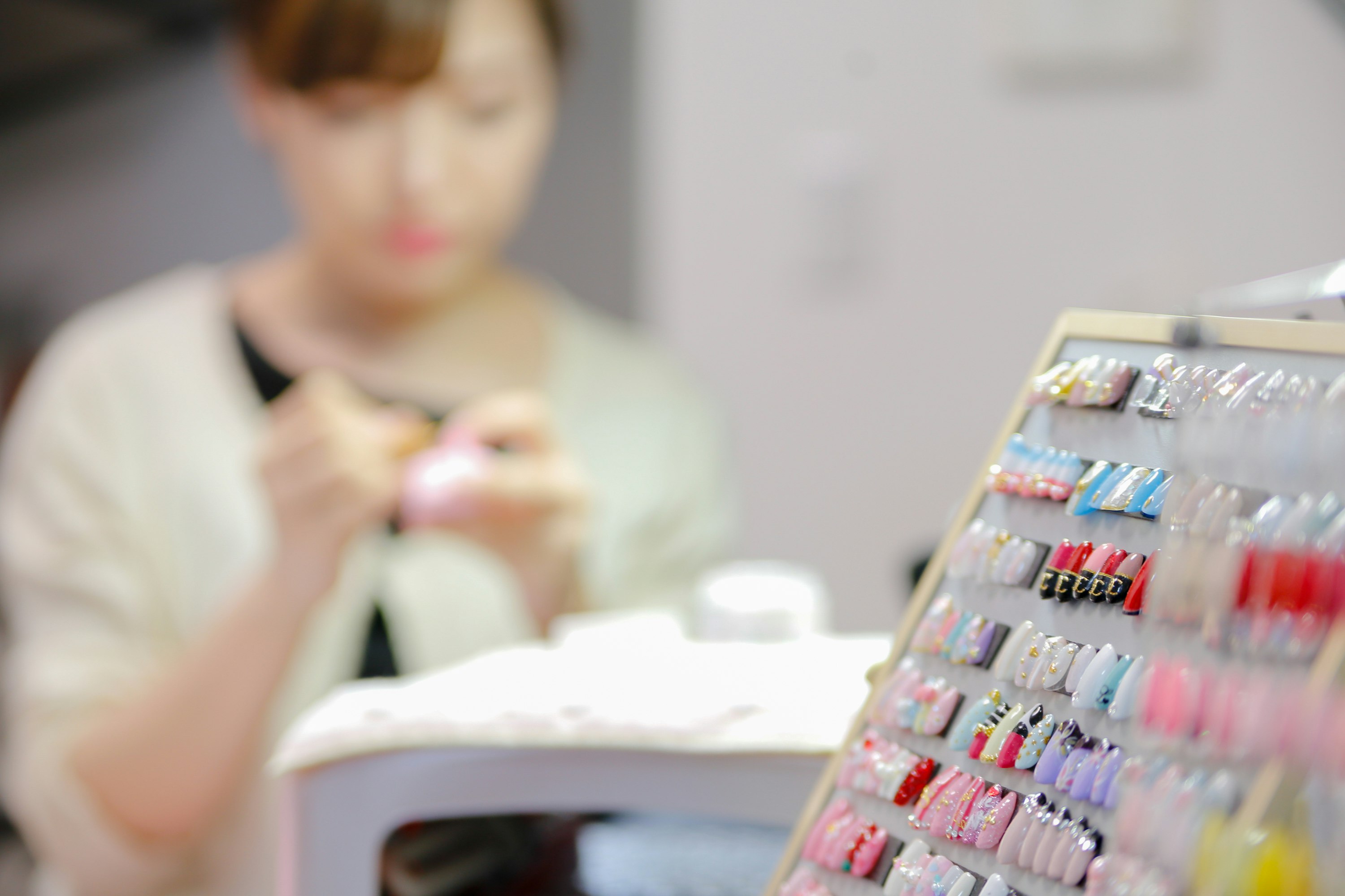 美甲店操作台上摆放的彩色指甲油与正在护理的手