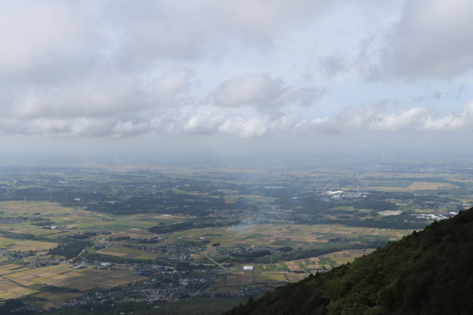 Paisaje expansivo desde la cima de la montaña con cielo nublado y colinas verdes