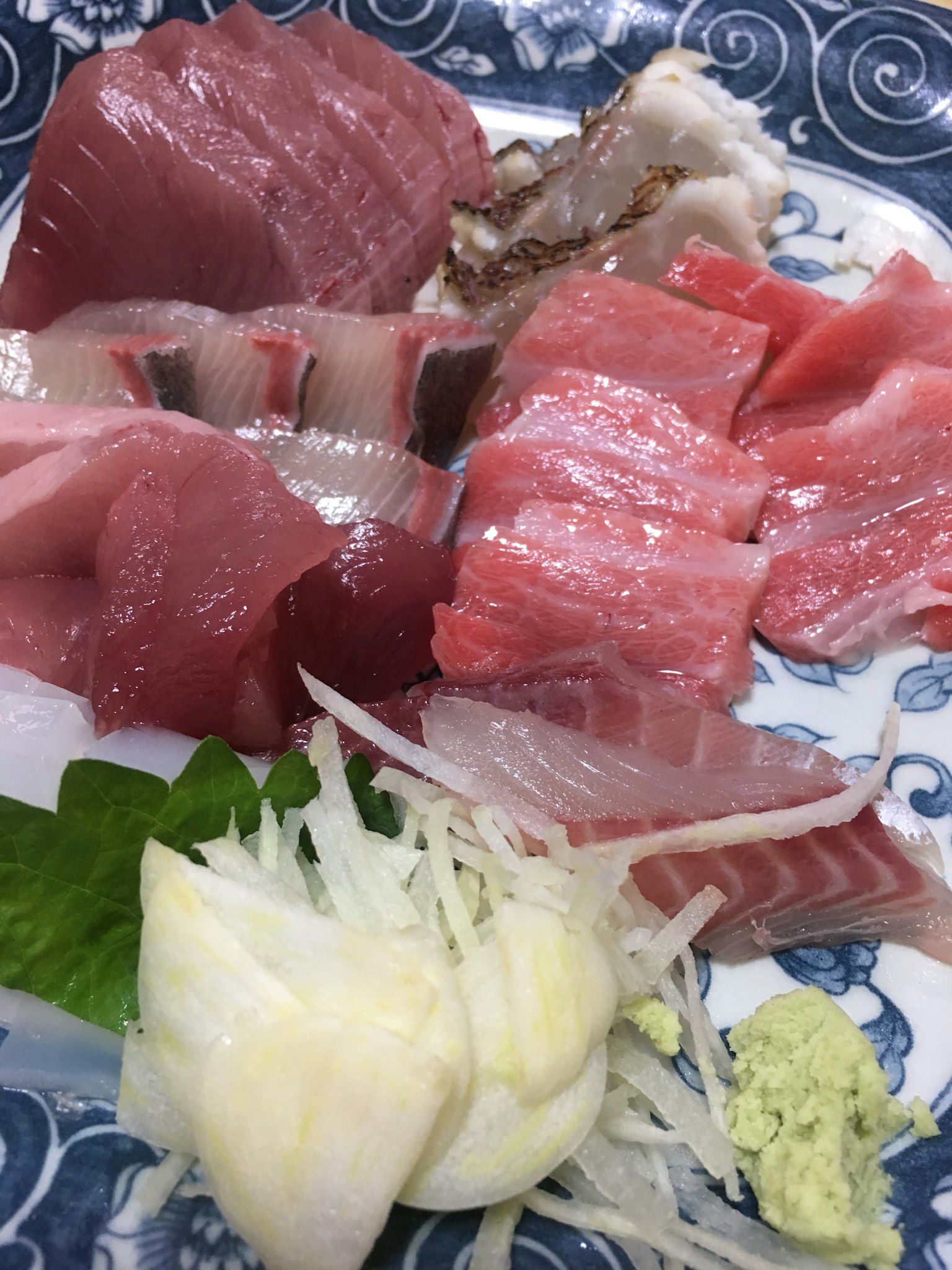 Plato de sashimi fresco con atún, jurel, wasabi, cebolla verde y lechuga
