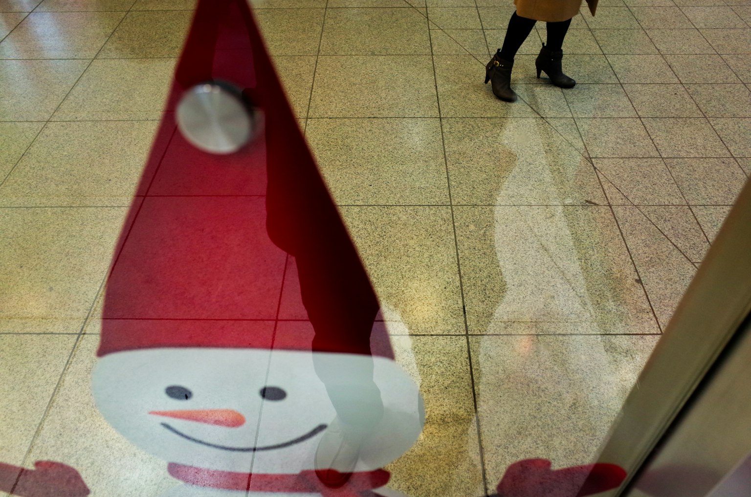 Ilustración de un muñeco de nieve con un sombrero rojo y la sombra de una persona