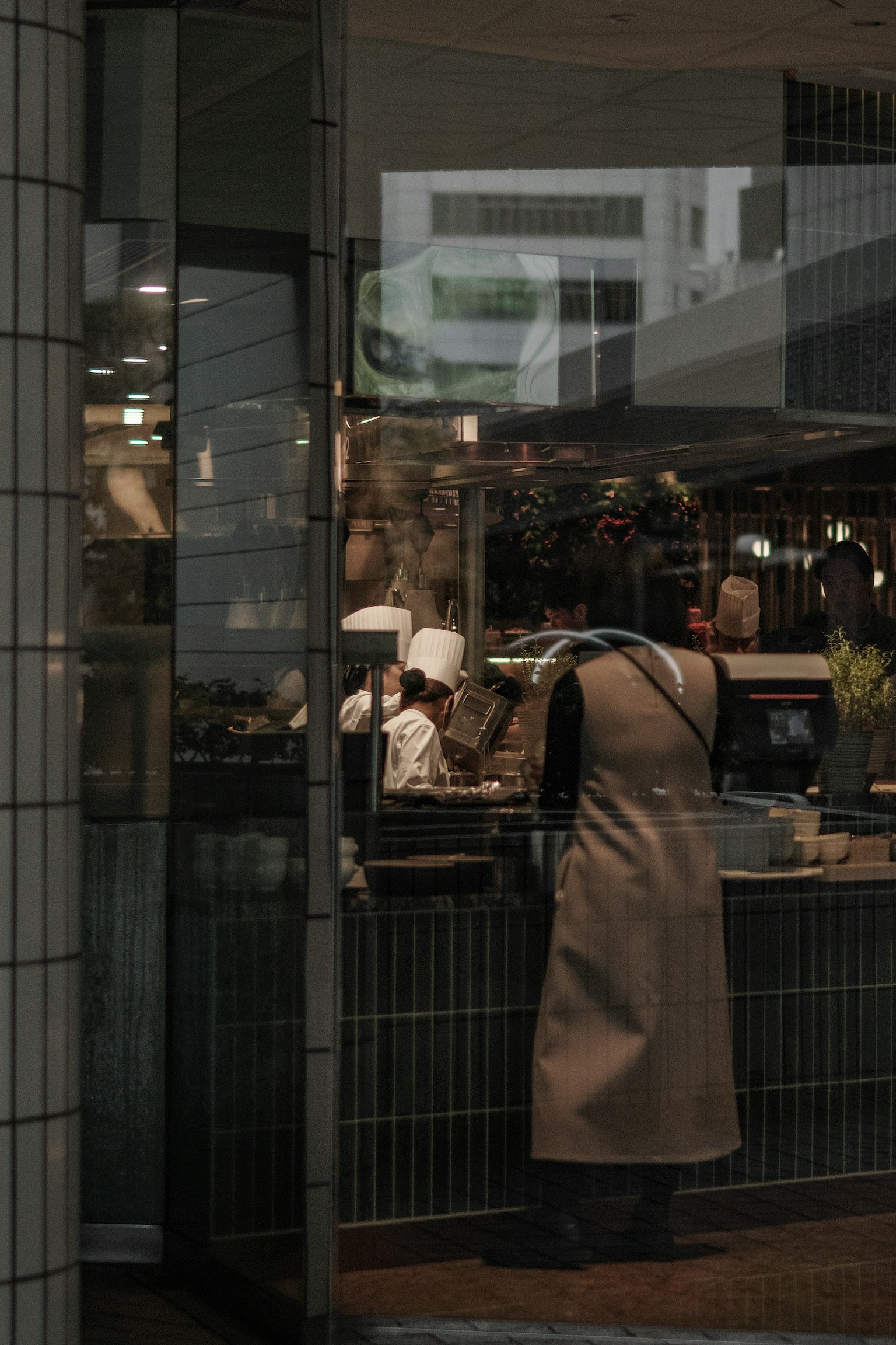Ein Koch, der durch Glas sichtbar ist, während er in einem Café Essen zubereitet