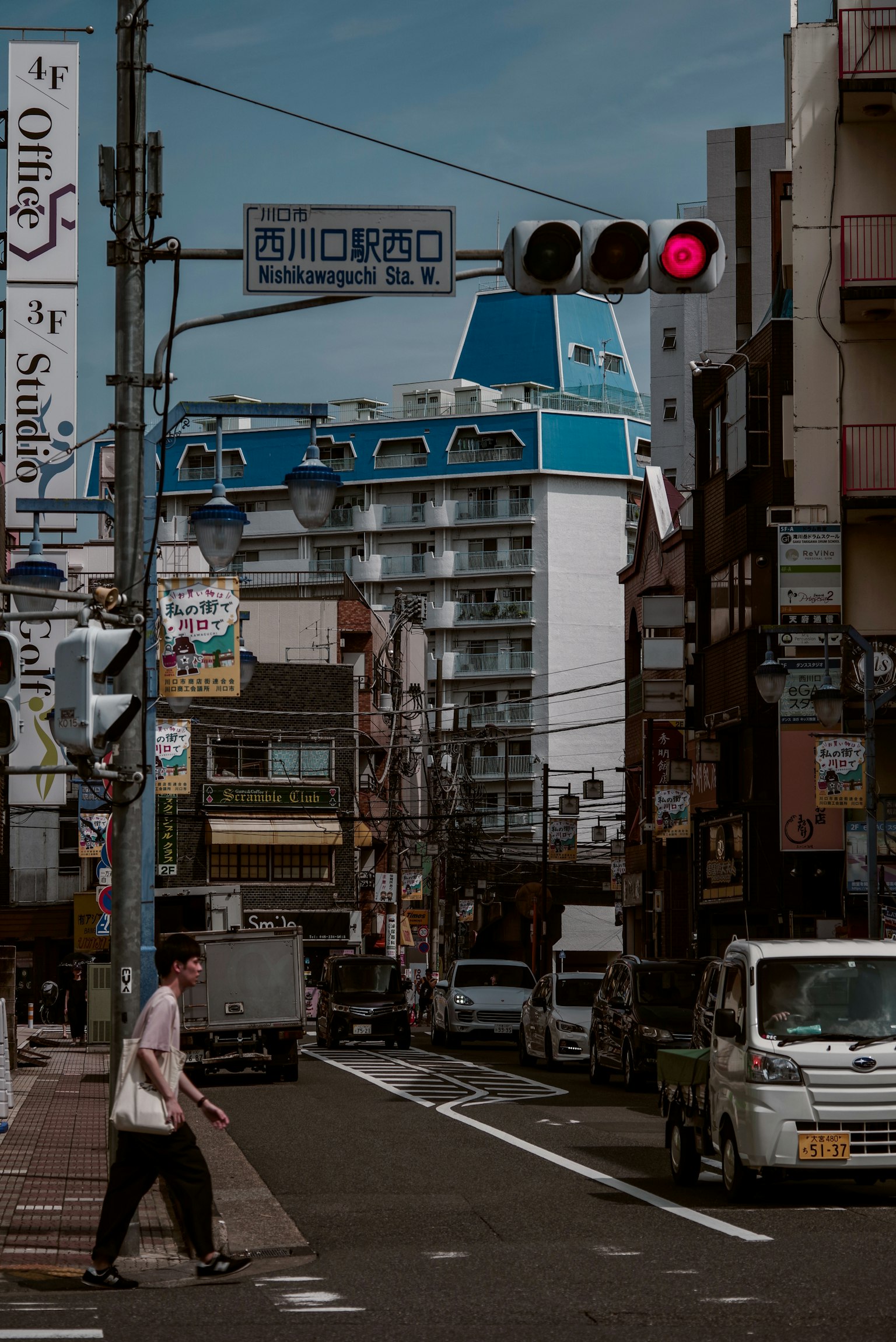 Seseorang menyeberang jalan di lampu merah di kota Jepang dengan bangunan atap biru