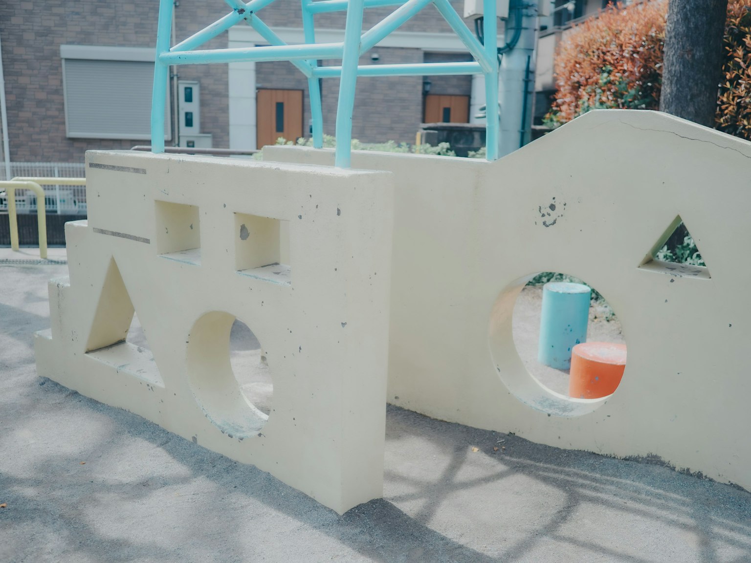 Estructura de parque infantil colorida de concreto amarillo con aberturas circulares y triangulares