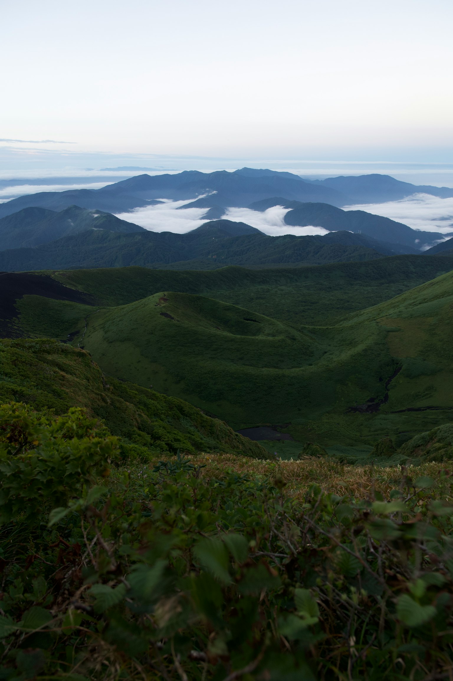 Mountain landscape with green hills and a sea of clouds