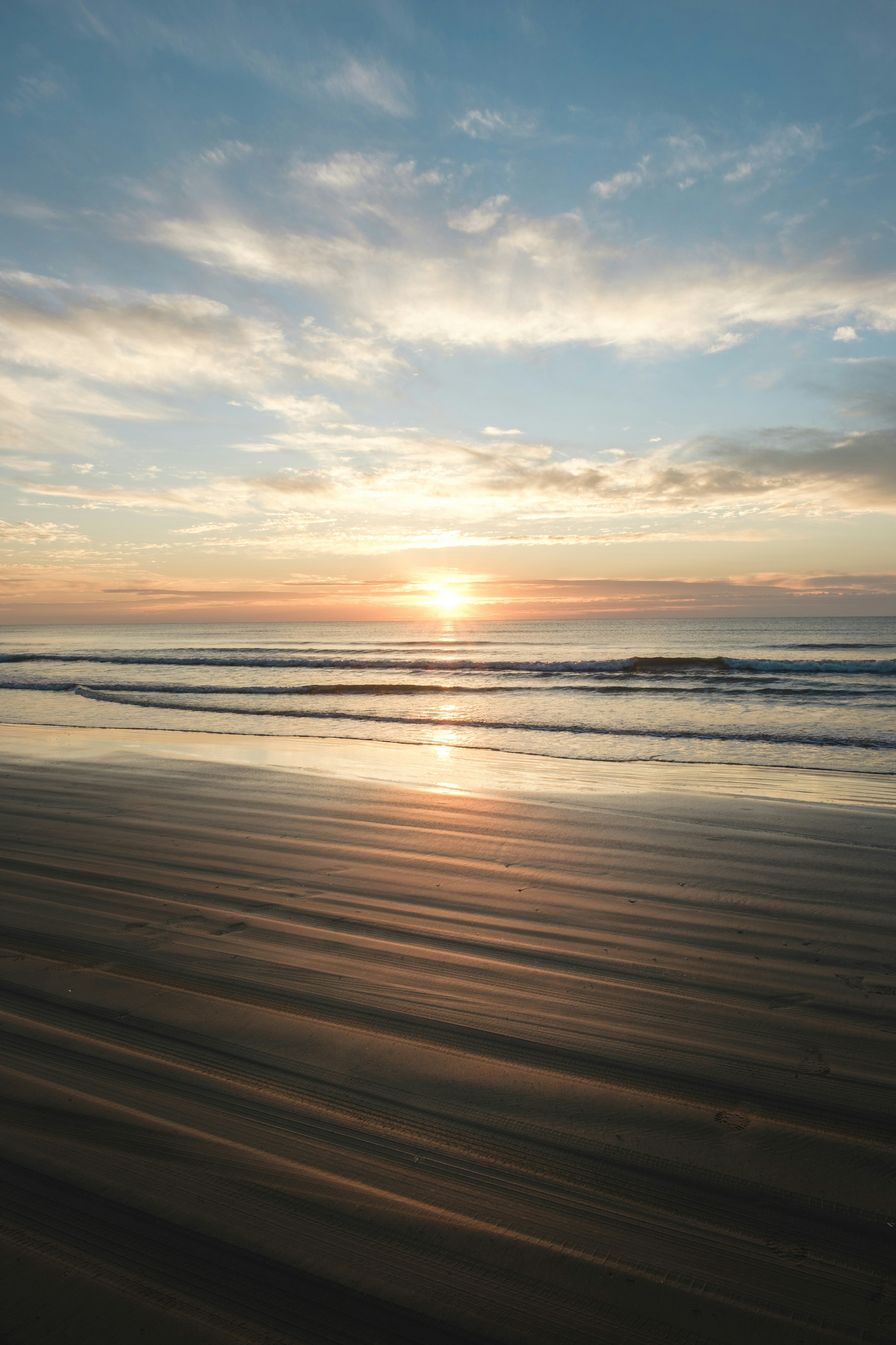 Sonnenuntergang am Horizont mit Wellen und Sandstrand