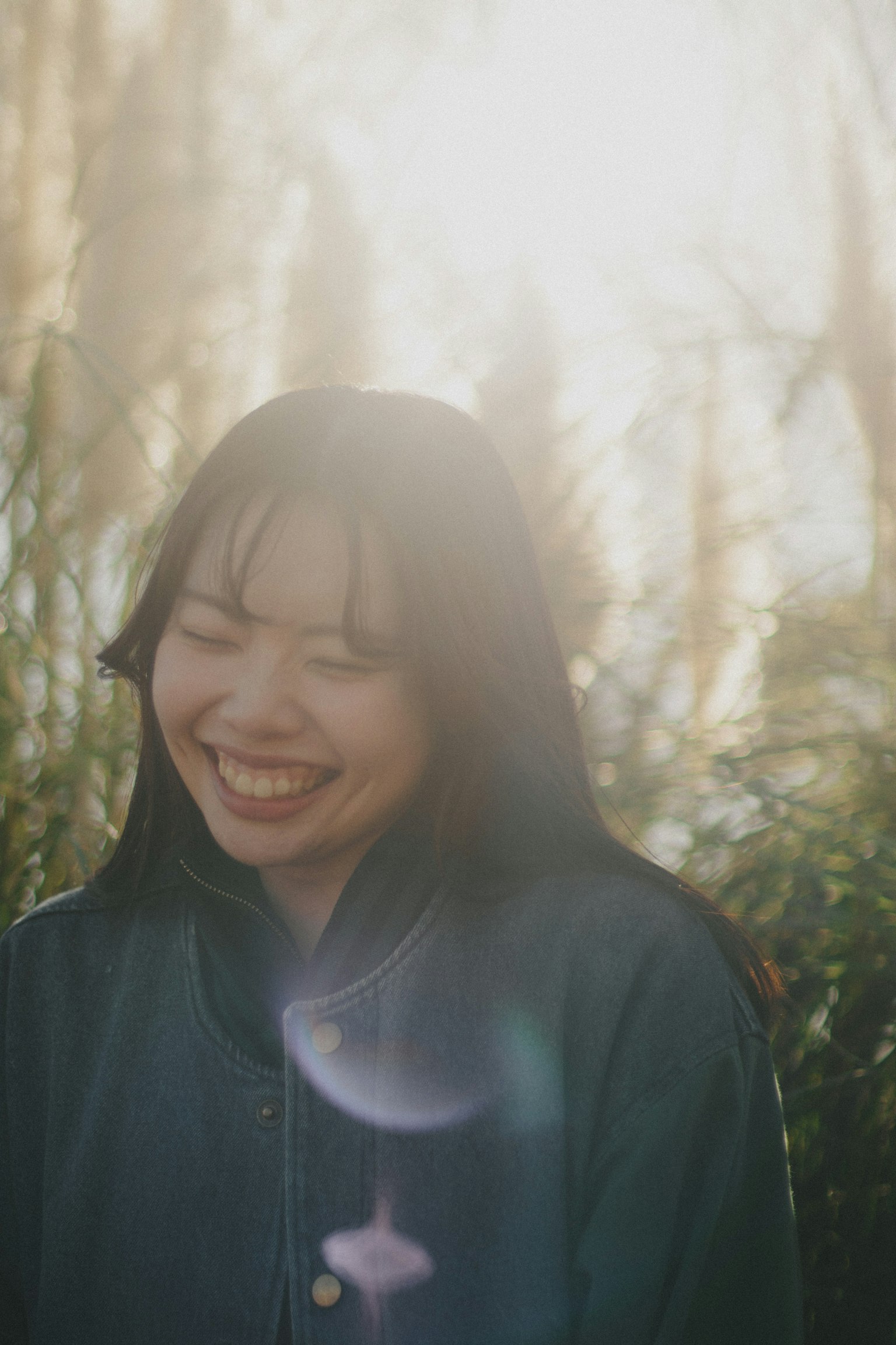 Femme souriante profitant de la lumière du soleil entourée par la nature
