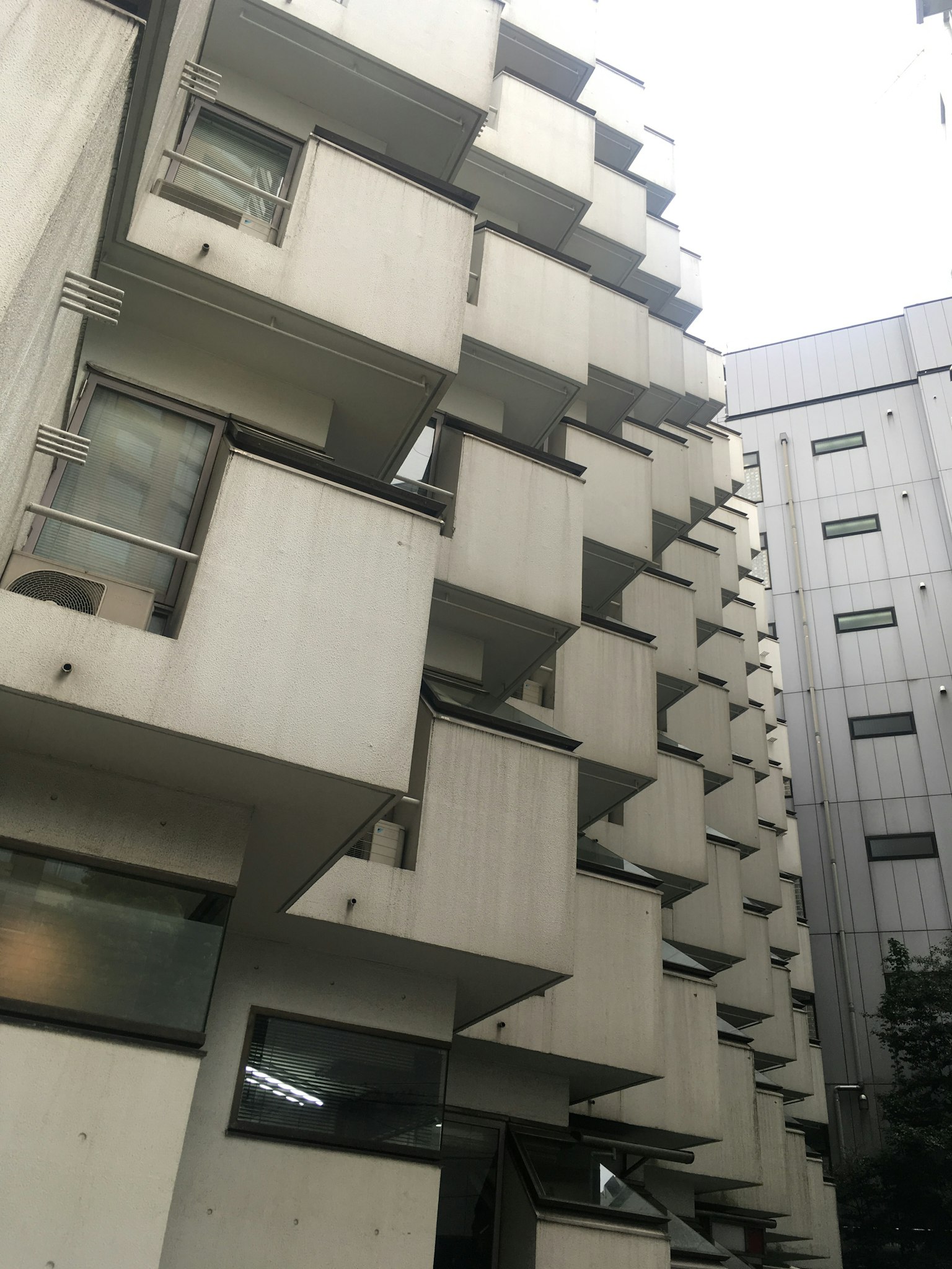 독특한 콘크리트 건물 외관과 각진 발코니 및 인접 구조물