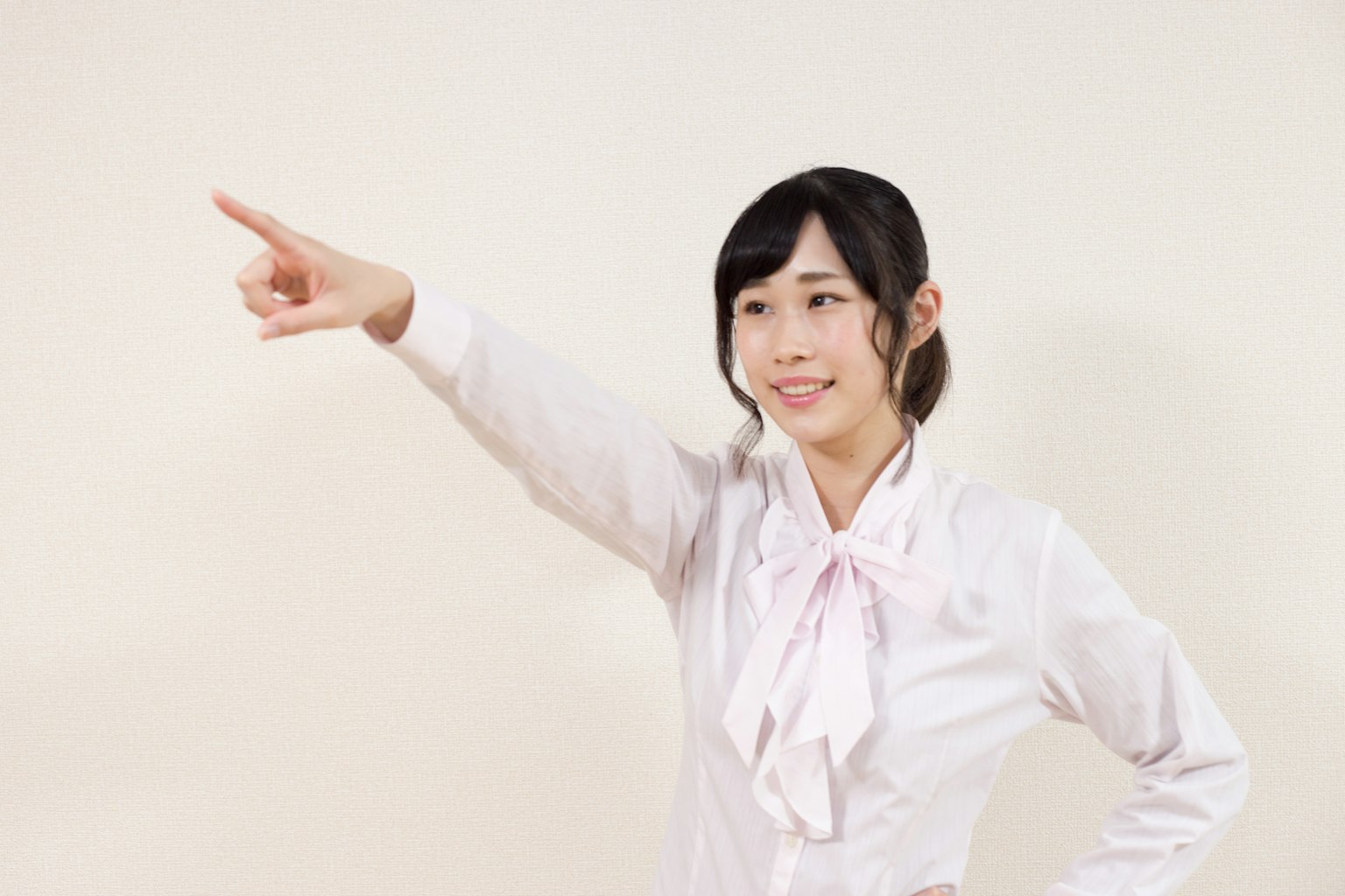 A woman in a white blouse smiling and pointing with her finger
