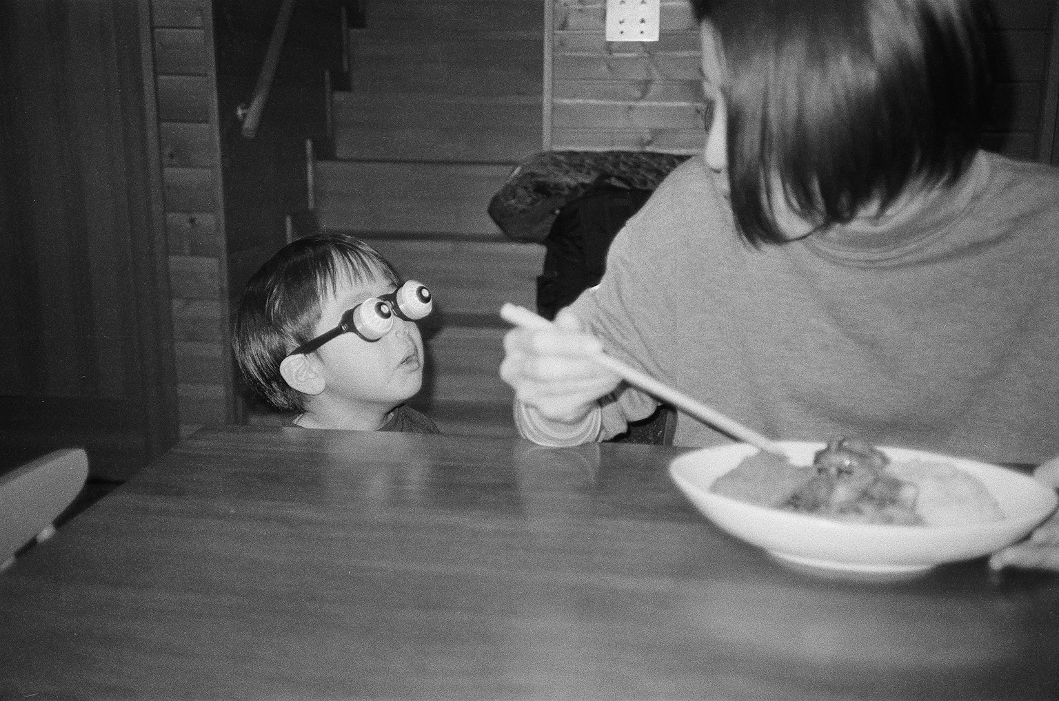 Un bambino con occhiali che guarda con sorpresa una donna in una foto in bianco e nero
