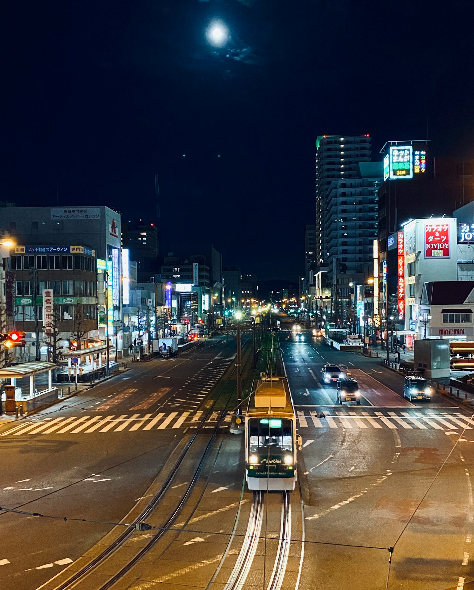 Paesaggio urbano notturno con luna splendente e tram a un incrocio
