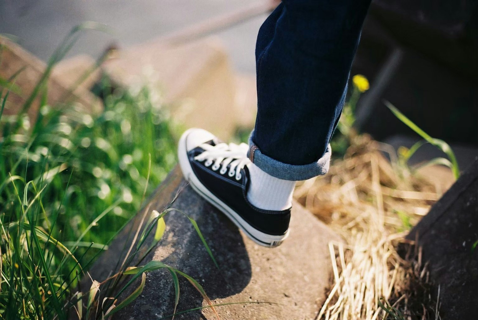 Pied dans des baskets noires se tenant sur l'herbe