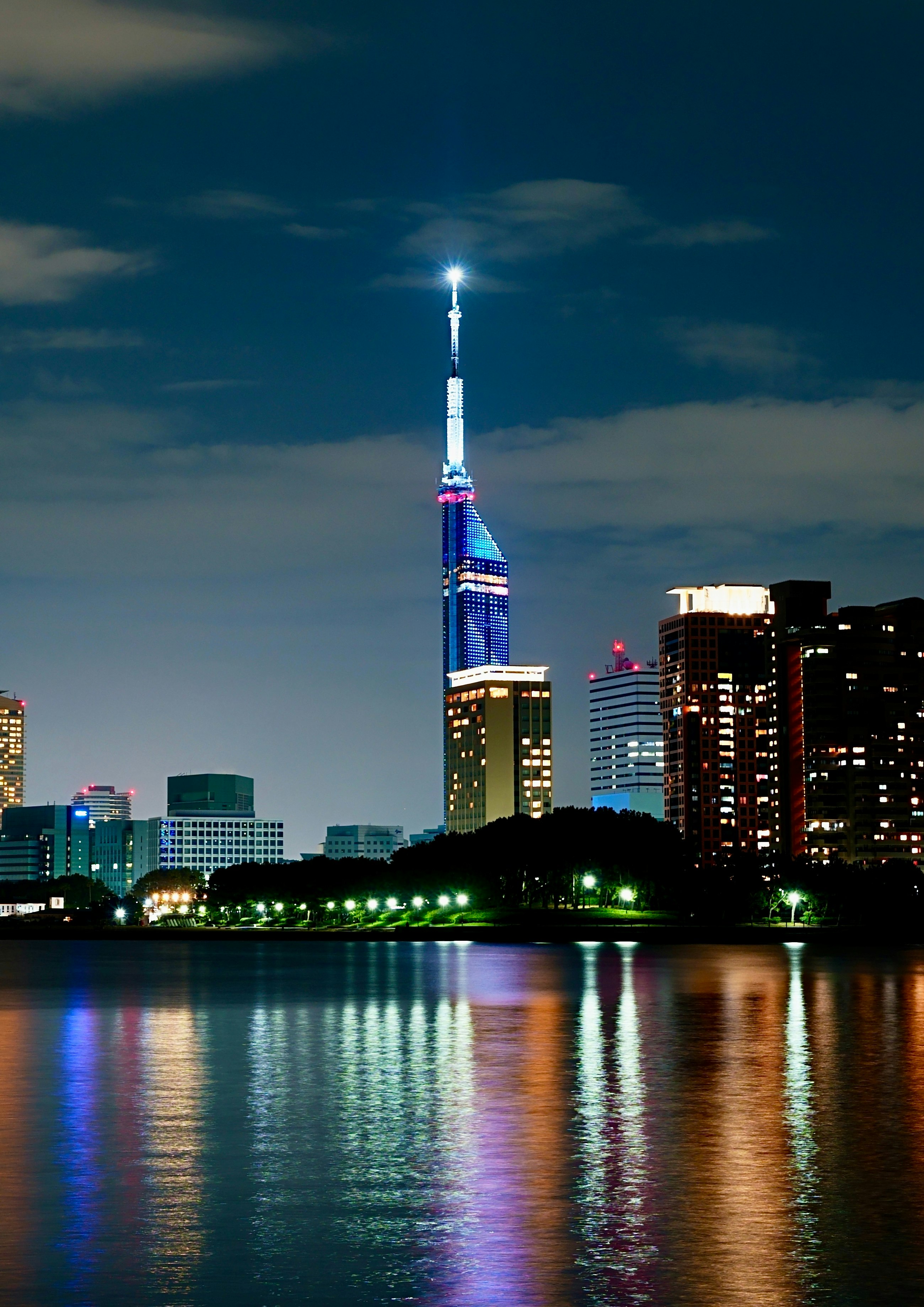 Skyline notturno di Fukuoka con riflessi sull’acqua