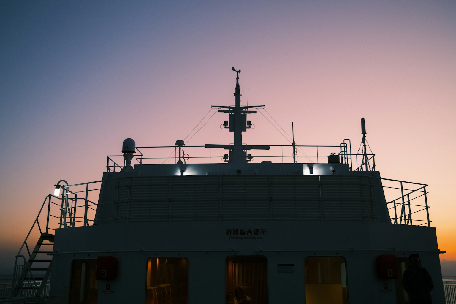 Silhouette de l'arrière d'un navire contre un ciel de coucher de soleil