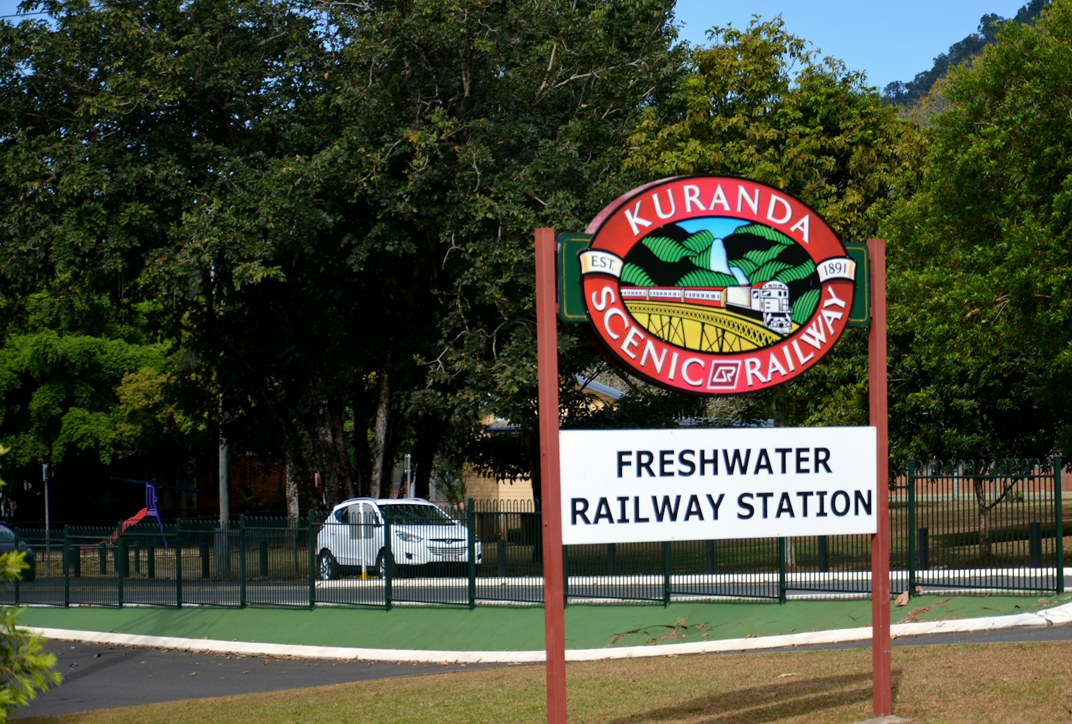 Sign for Kuranda Scenic Railway at Freshwater Railway Station surrounded by lush greenery