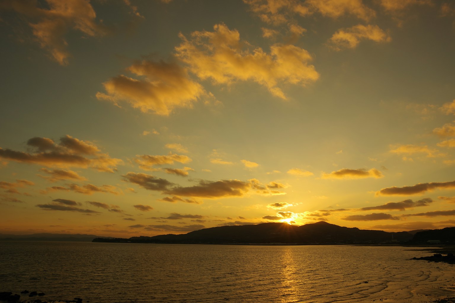 Schöner Sonnenuntergang hinter Bergen über dem Meer