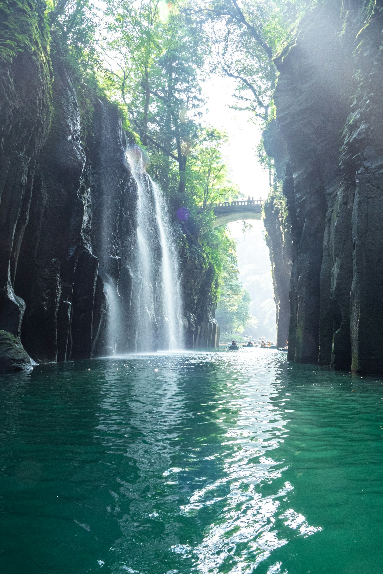 Pemandangan ngarai dengan air terjun dikelilingi oleh pepohonan refleksi di permukaan air