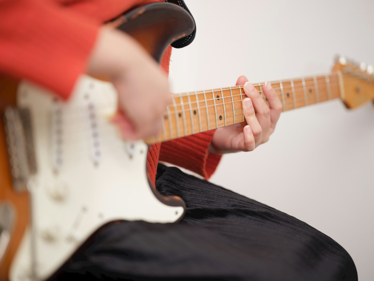 Person in red clothing playing an electric guitar