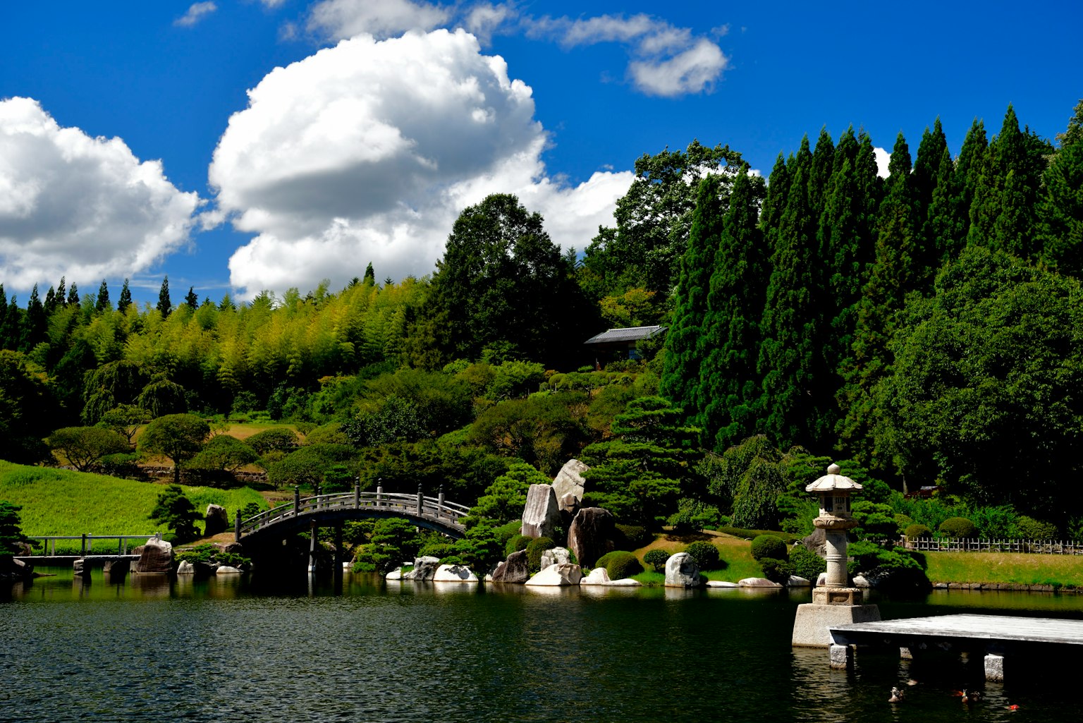 Vue pittoresque d'un jardin japonais traditionnel avec un pont sur un étang et des lanternes en pierre