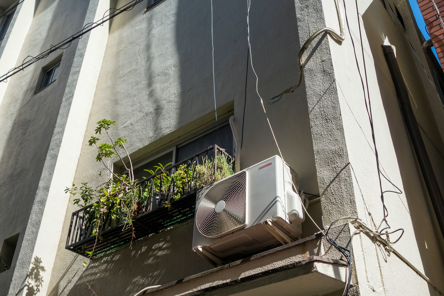 Air conditioning unit mounted on a building wall with a planter