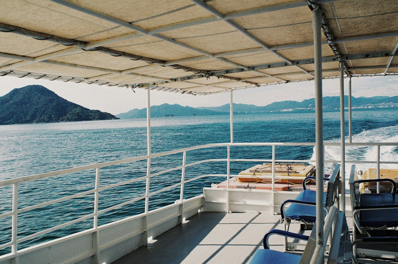 Deck eines Bootes mit Blick auf das ruhige Meer und entfernte Berge