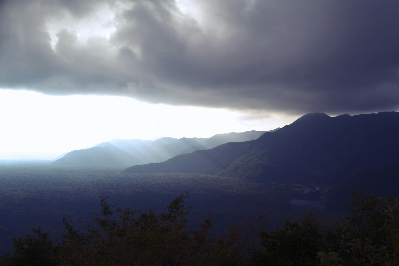 Pemandangan gunung dramatis dengan awan gelap dan sinar cahaya