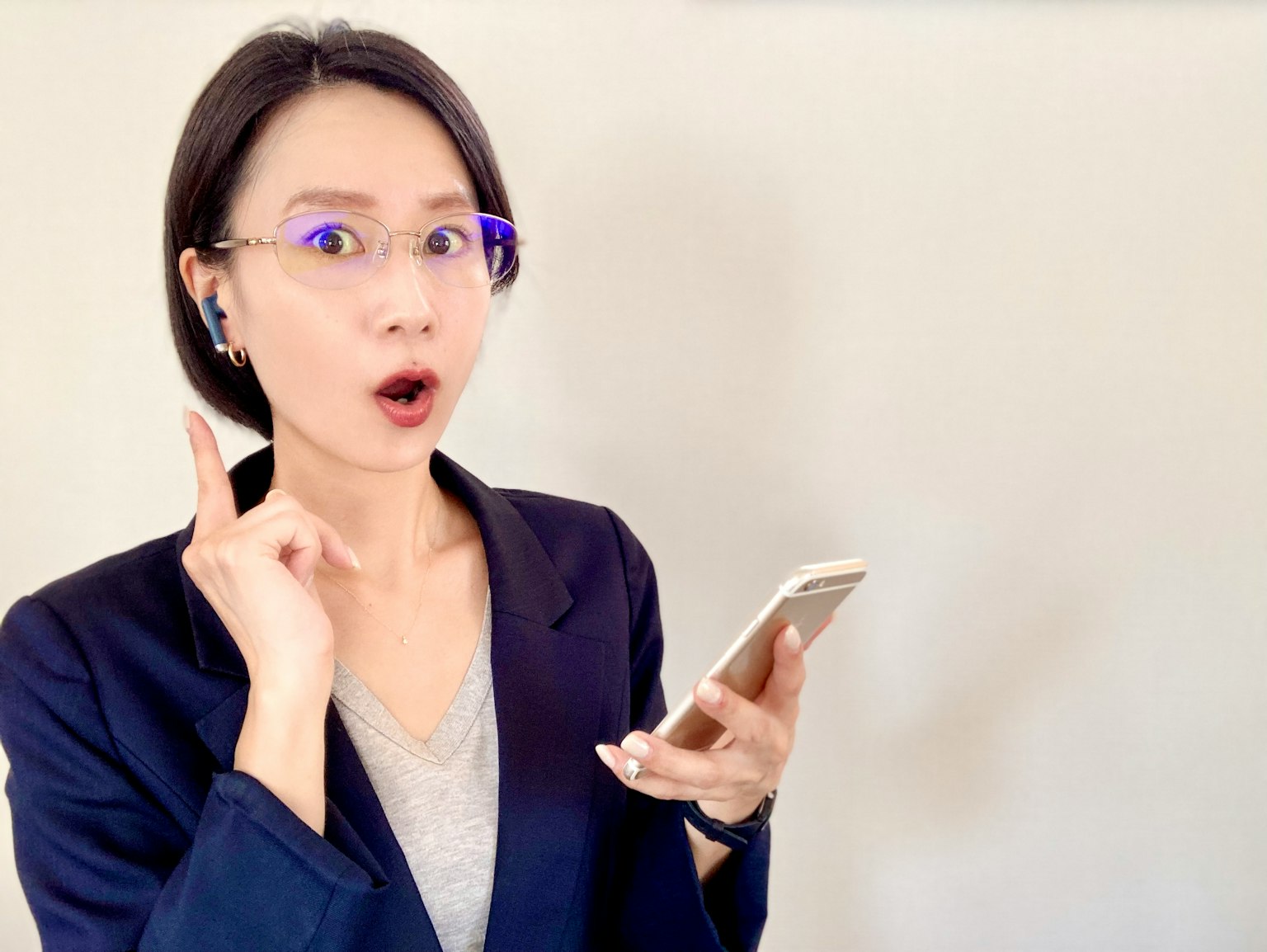 一位女性在商务环境中拿着智能手机，表情惊讶