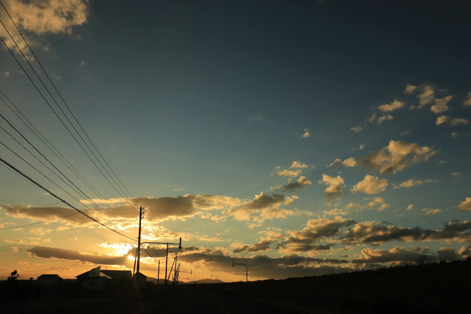 Silhouette von Wolken und Stromleitungen vor einem Sonnenuntergangshimmel