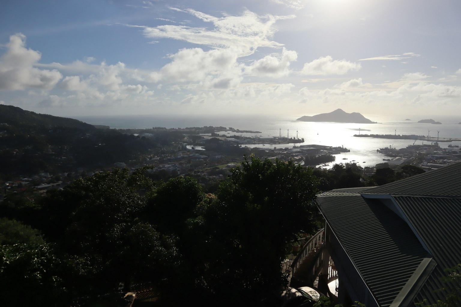 Vista panoramica dell'oceano e del cielo blu con alberi vicini e un'isola lontana