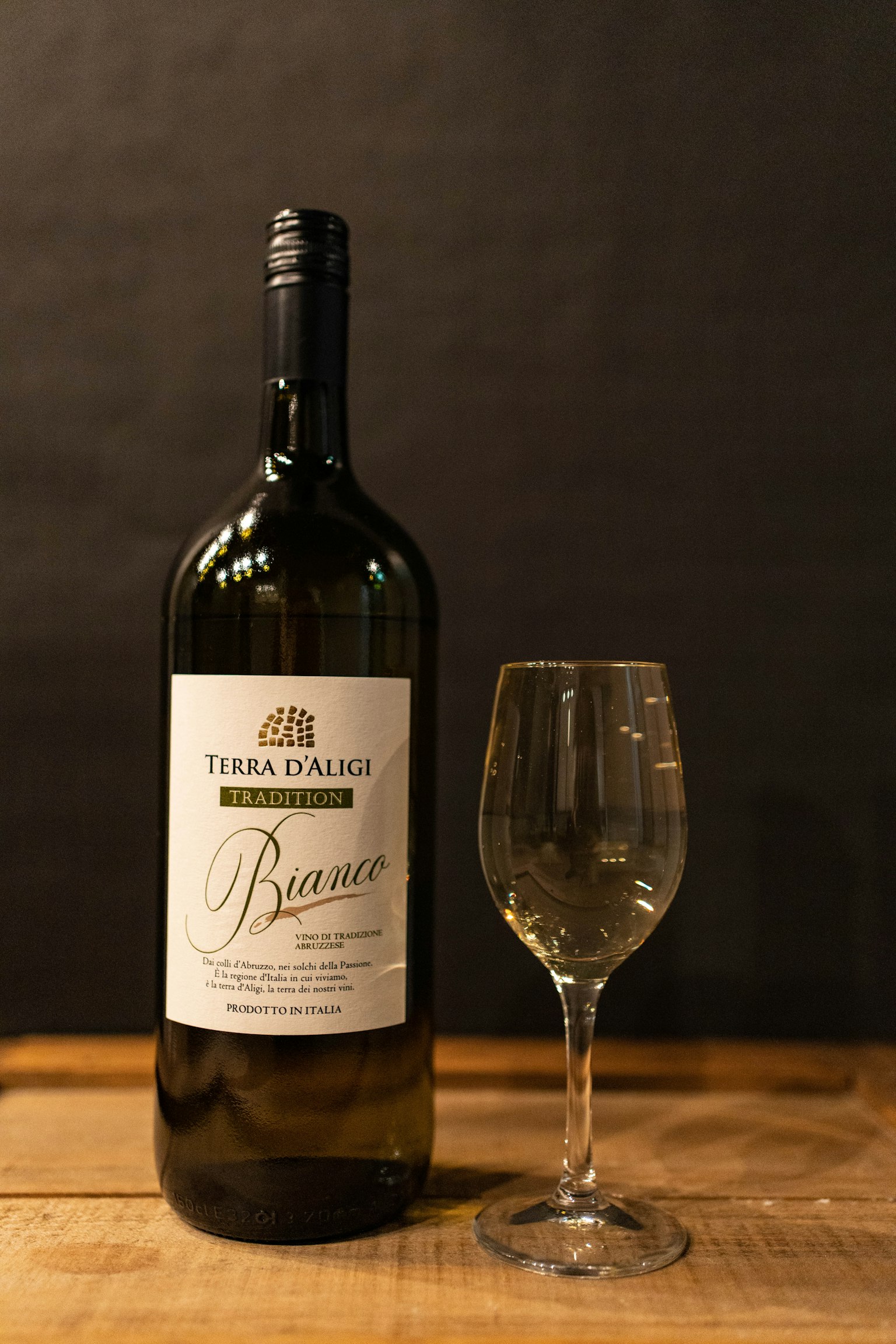 Una bottiglia di vino bianco e un bicchiere da vino su un tavolo di legno