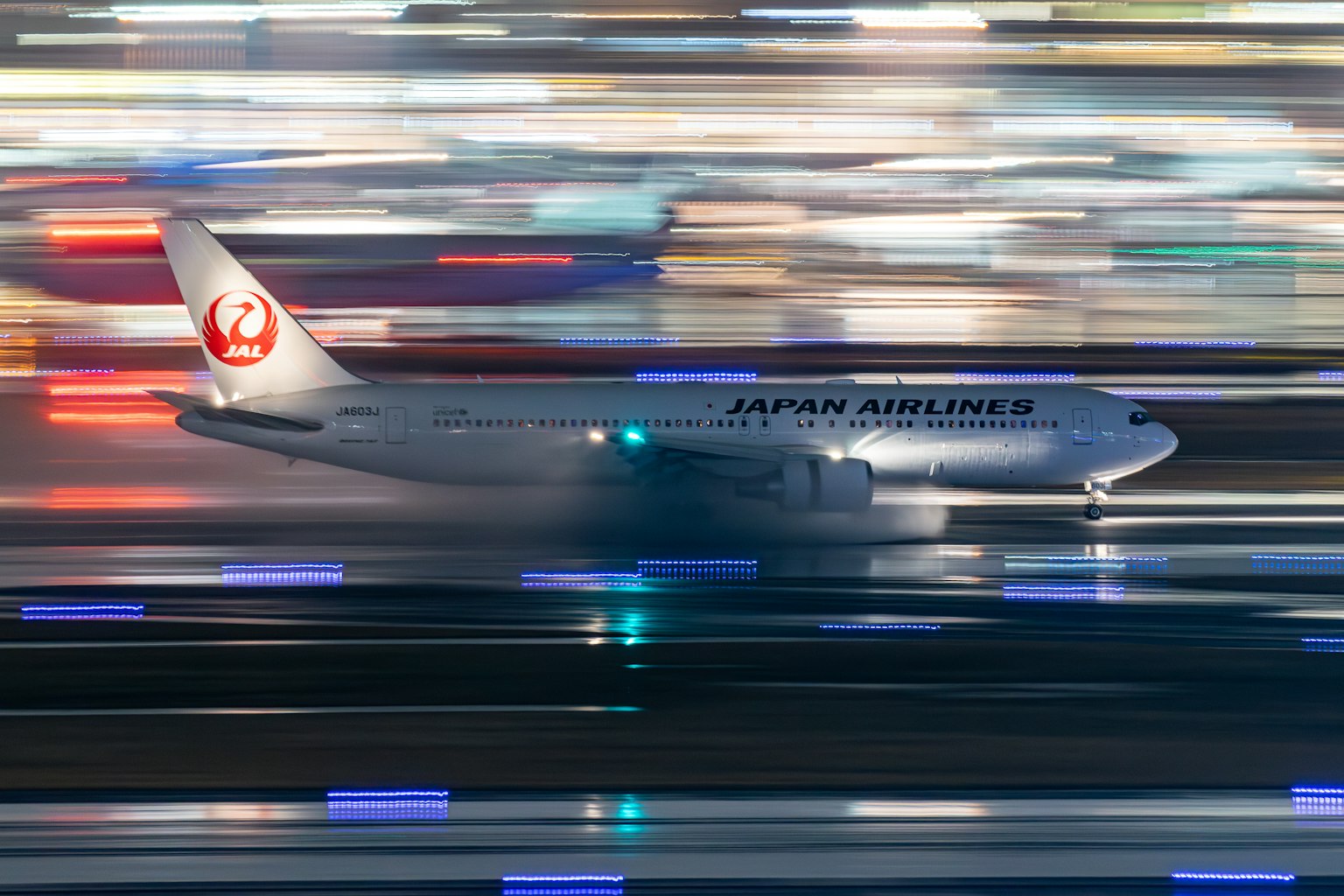 Máy bay Japan Airlines di chuyển nhanh trên đường băng với hiệu ứng mờ chuyển động