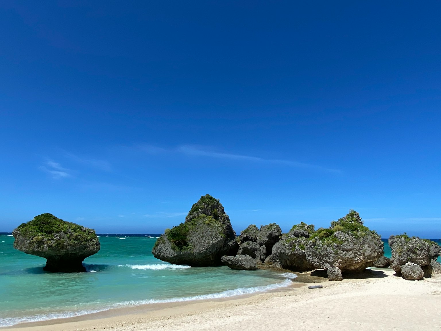 Formasi batu unik di pantai dengan air turquoise jernih dan langit biru cerah