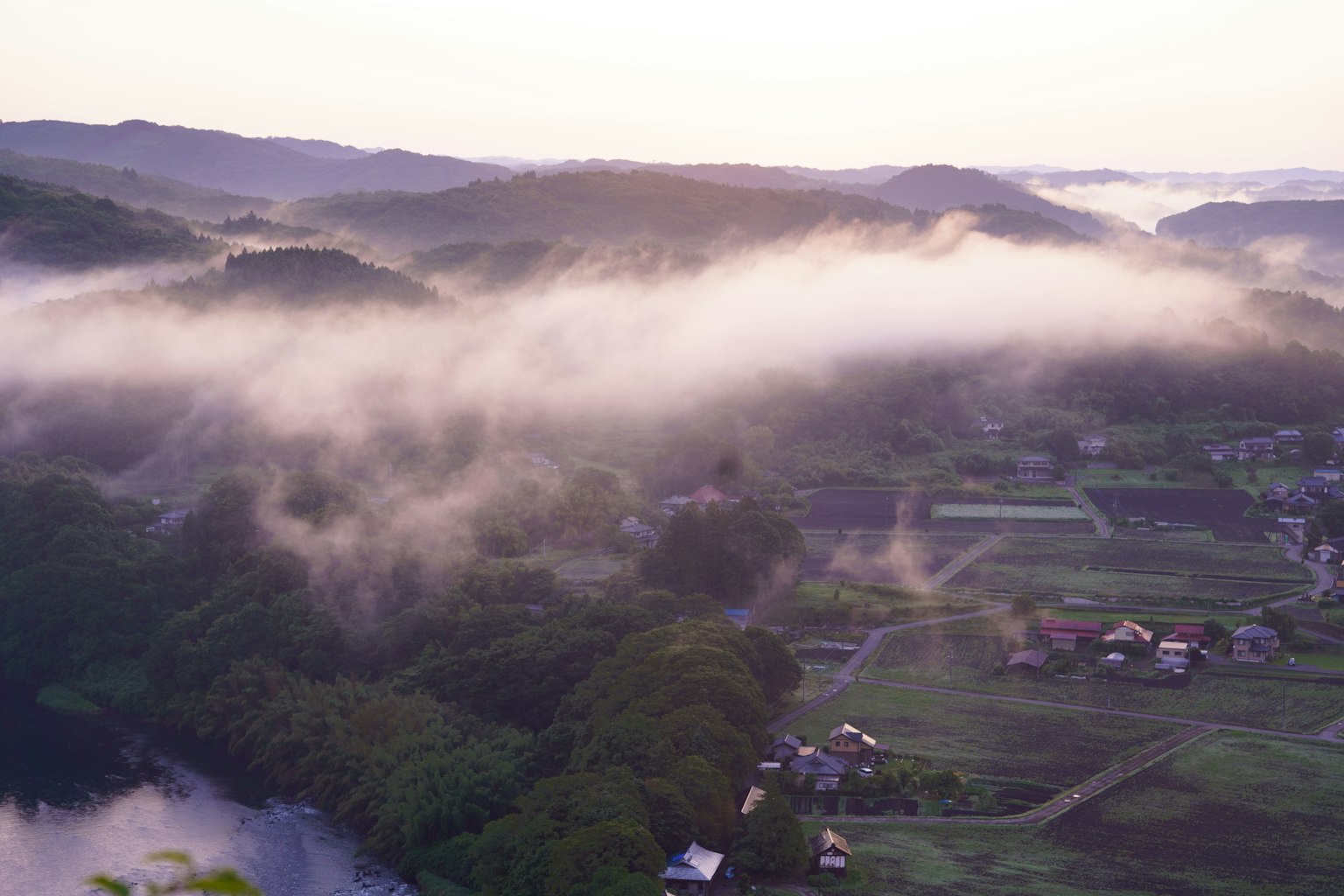 Vista mattutina panoramica di montagne avvolte nella nebbia e paesaggio rurale