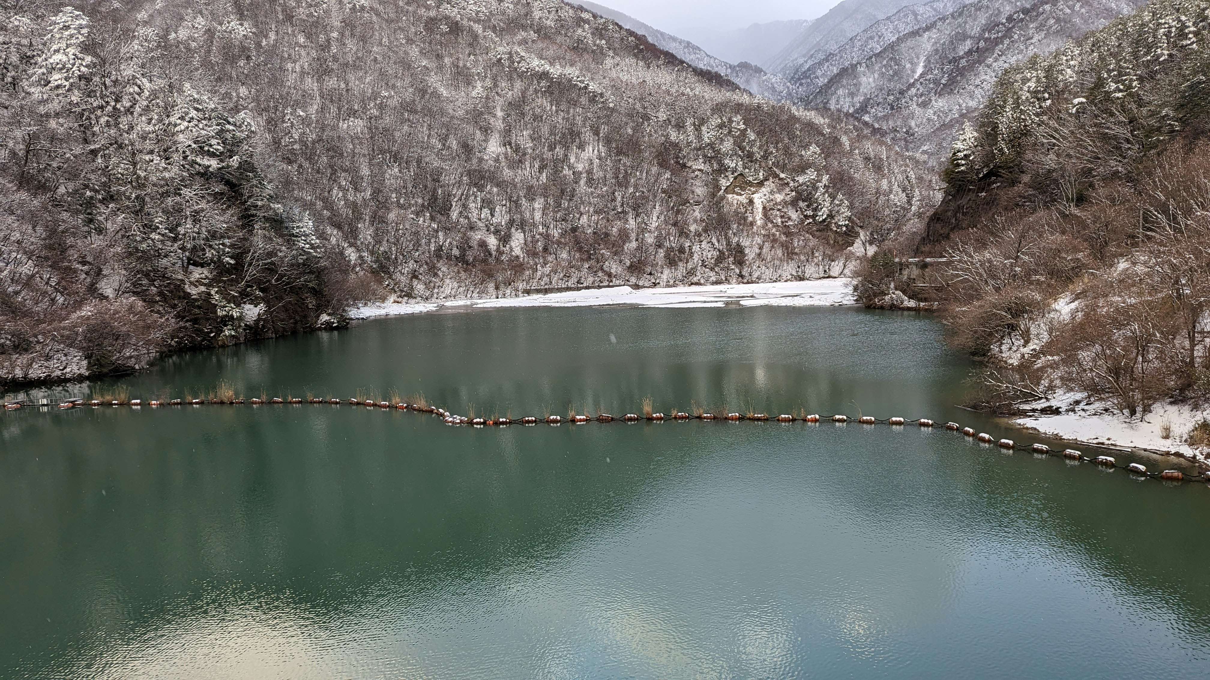 雪の残る渓谷の湖と山並み