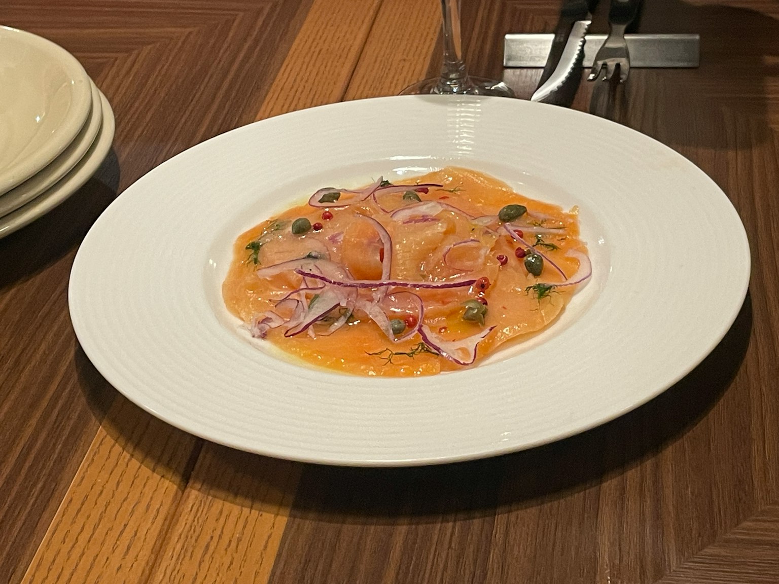 Teller mit Ravioli in orangener Sauce garni mit Kräutern