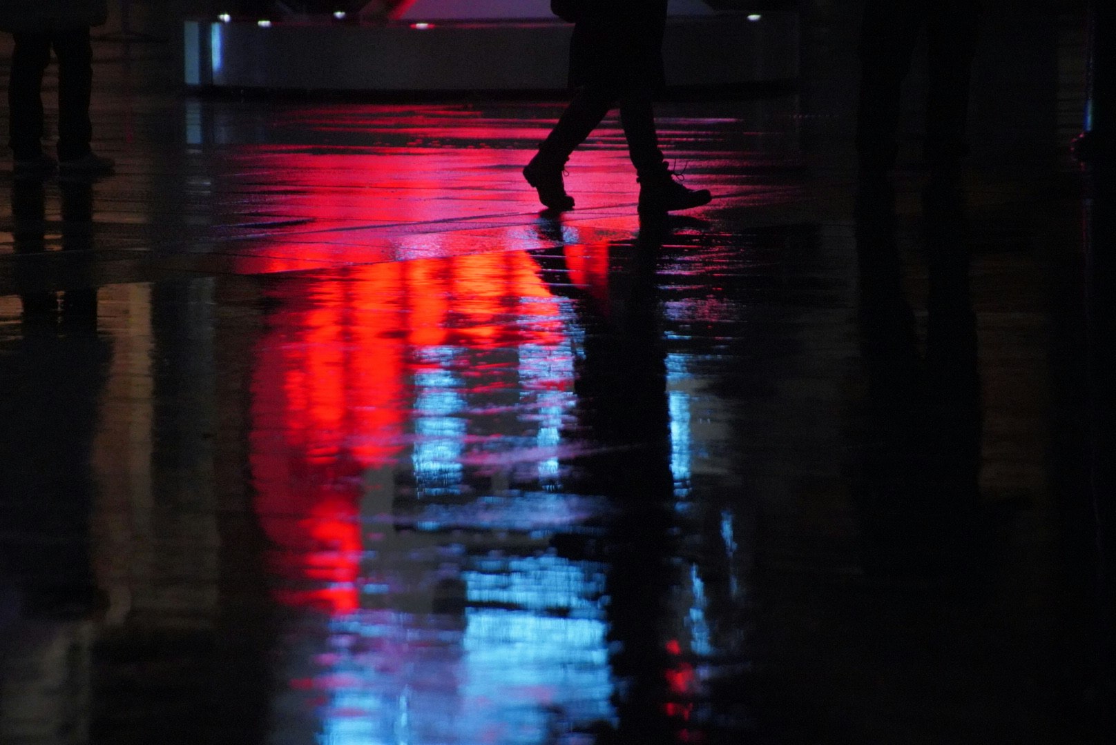 雨上がりの路面に映る赤と青のネオン光のある夜の街並み