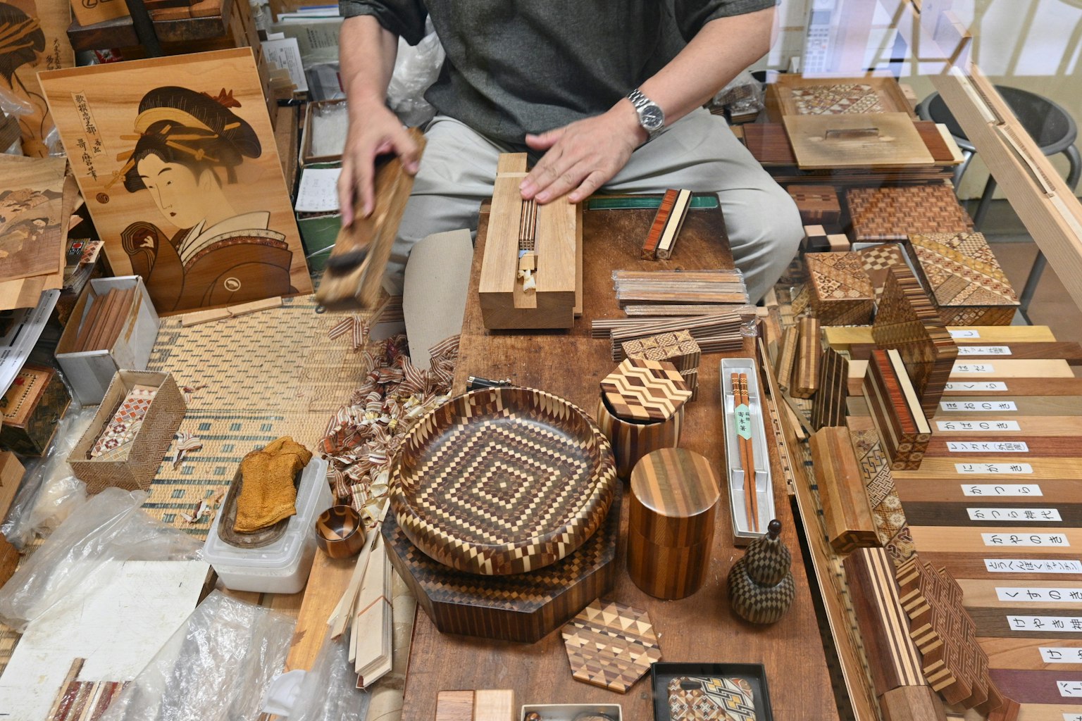 Artesano trabajando en artesanía de madera rodeado de varios objetos de madera