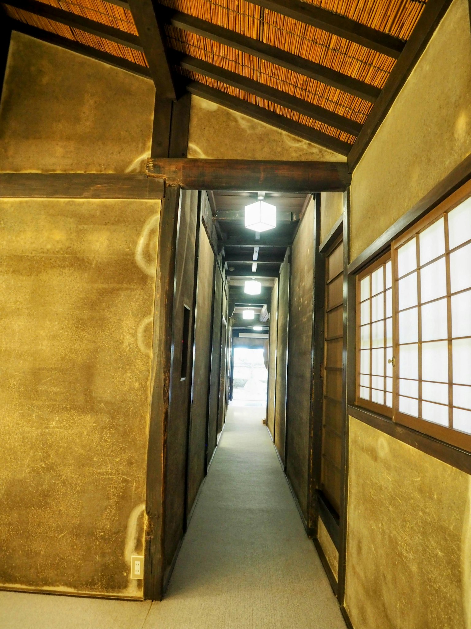 Innenansicht eines traditionellen japanischen Flurs mit hellem Licht und Wänden aus Lehm und Holz