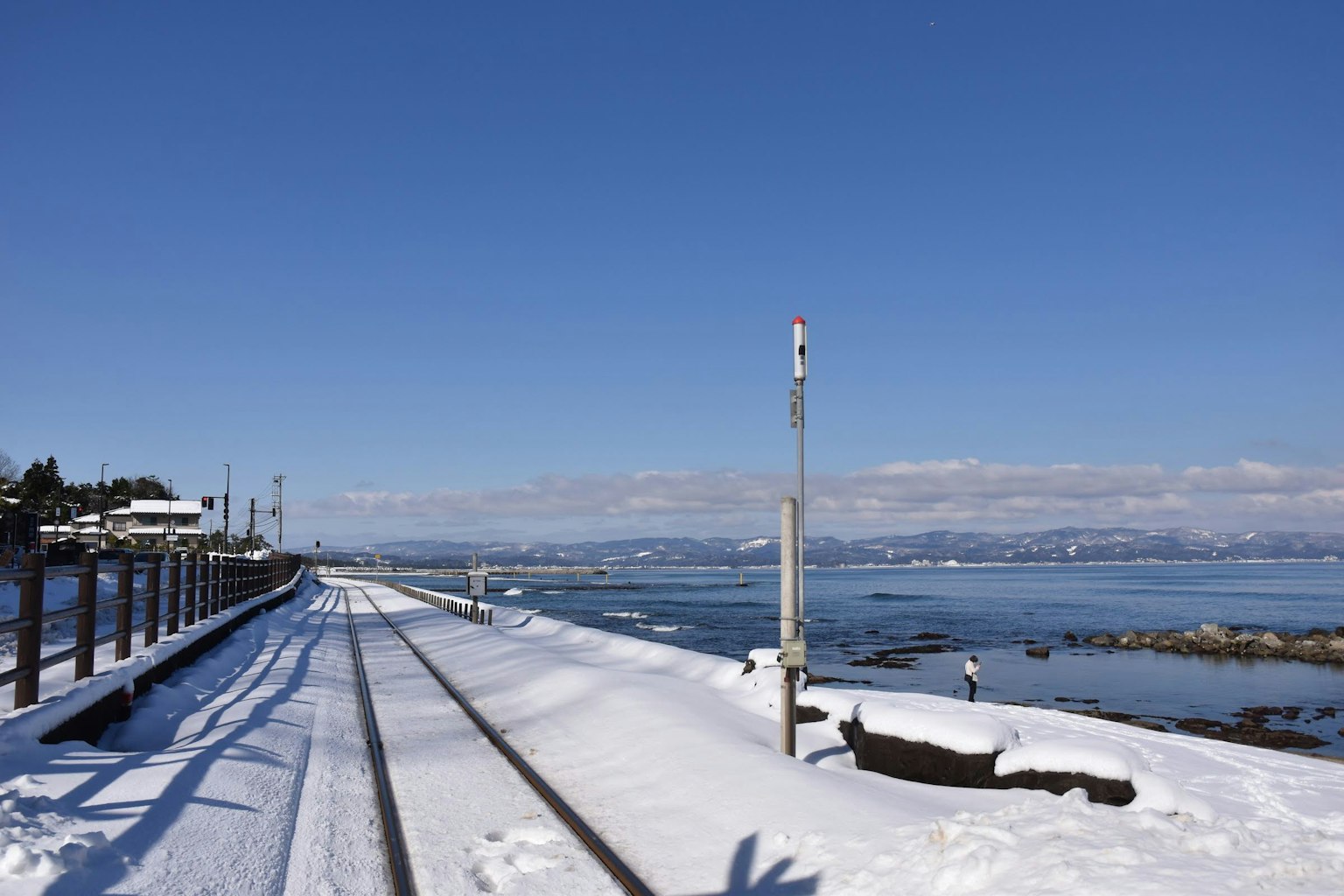 Chemin de fer enneigé à côté d'une mer bleue sous un ciel clair