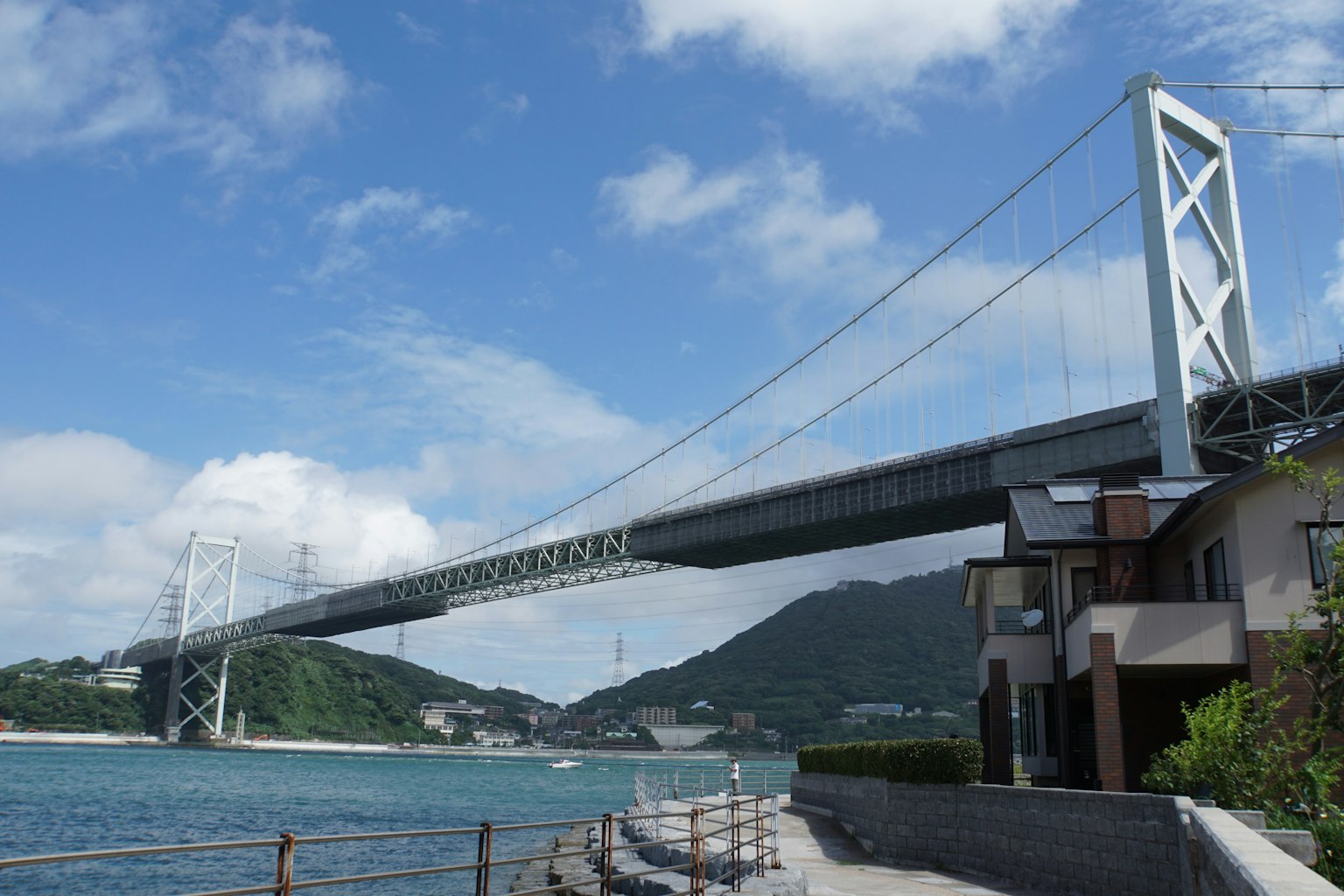 Un gran puente colgante se extiende sobre el mar con montañas al fondo