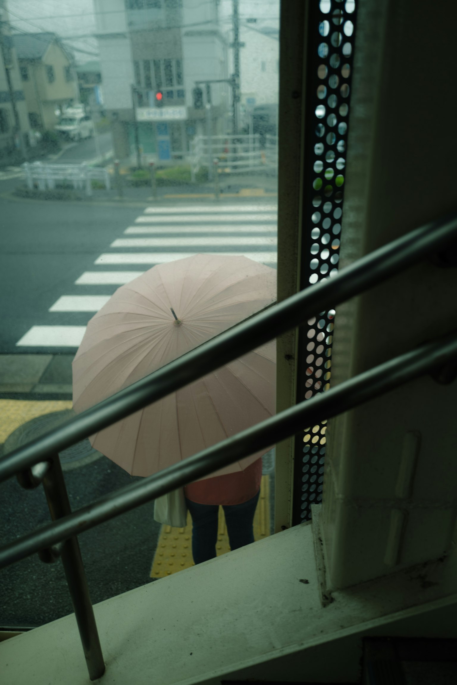 Une personne tenant un parapluie rose se tenant près d'un passage piéton