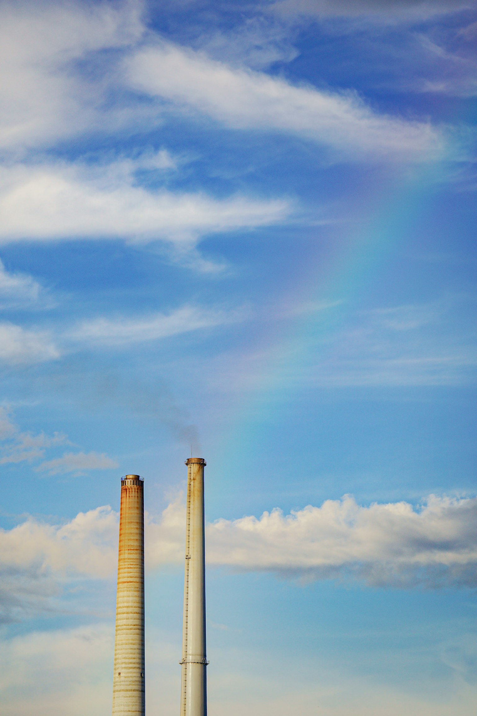 Ciminiere contro un cielo blu con un arcobaleno