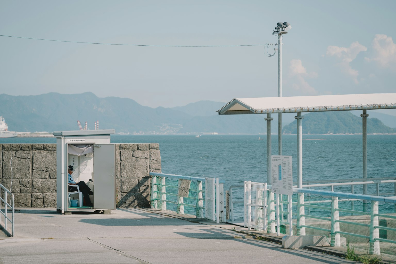 Puerta abierta en un muelle con una persona y vista al océano