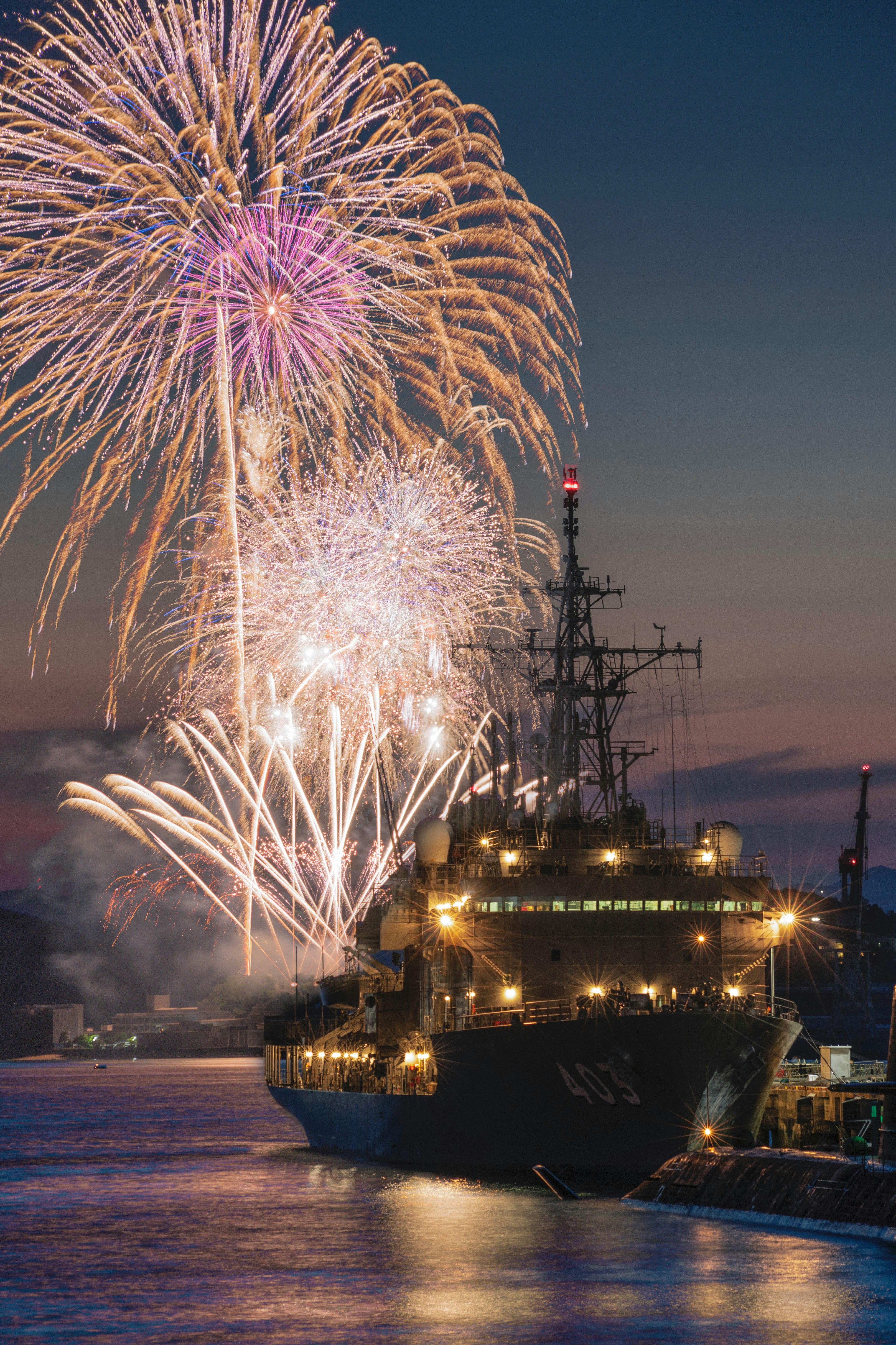 海上自衛隊の艦艇と花火が夜空に広がる海上祭の光景