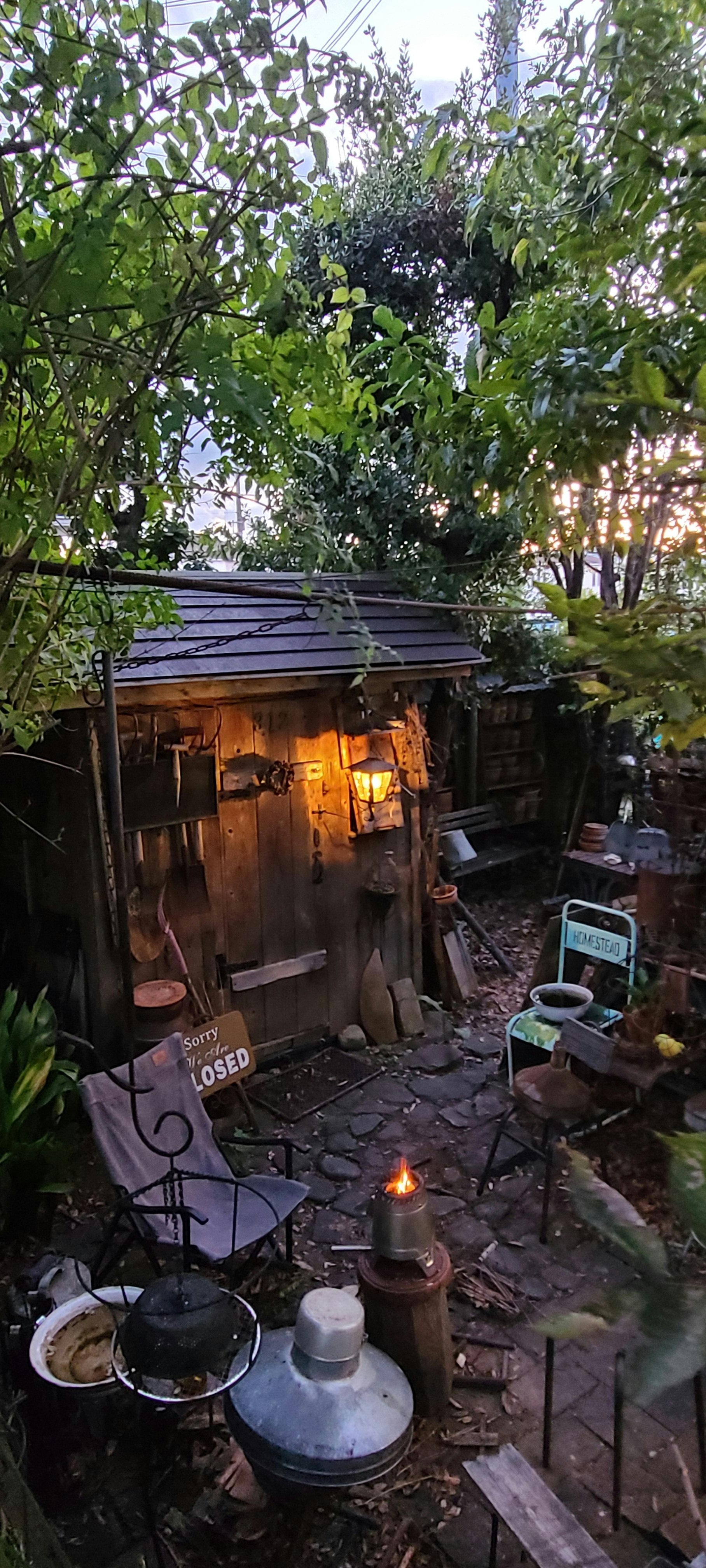wood stove and firewood around a backyard fire at dusk