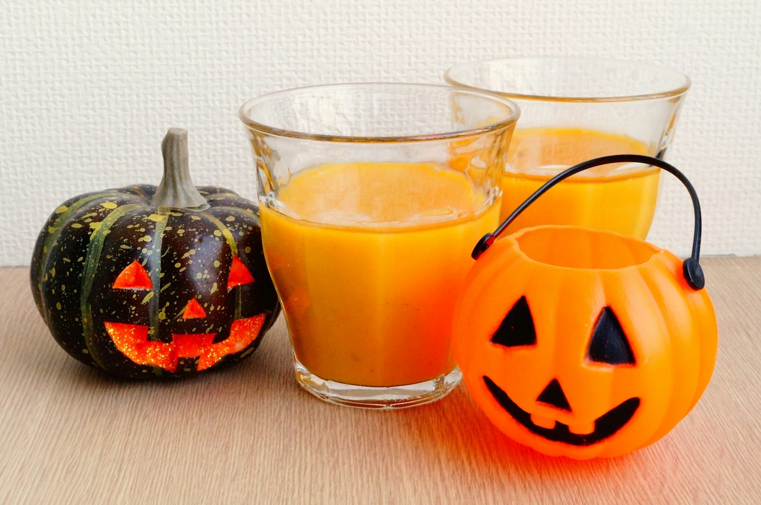 Mesa con decoraciones de Halloween y vasos de jugo de naranja